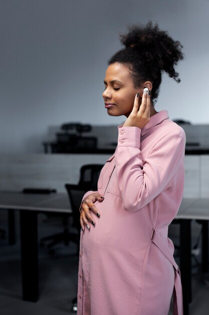 Medium shot pregnant woman wearing earphones