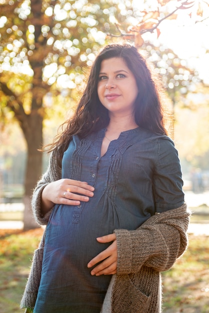 Средний снимок беременной женщины с голубыми глазами позирует