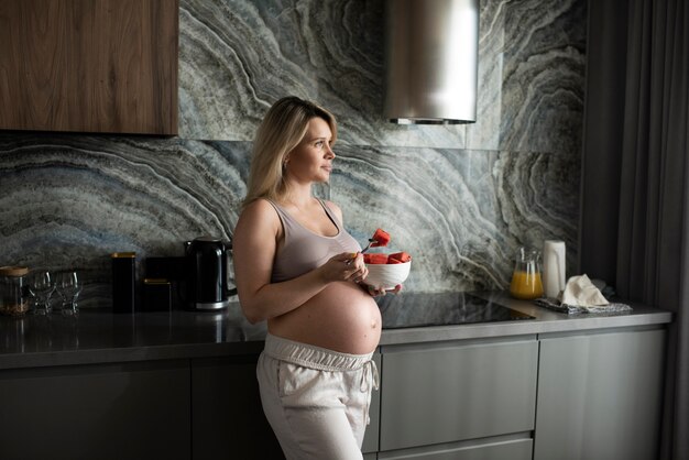 Medium shot pregnant woman with fruit bowl