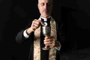 Free photo medium shot priest holding eucharist