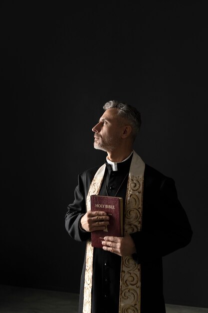 Medium shot priest holding holy bible