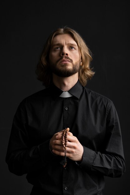 Medium shot priest playing with rosary