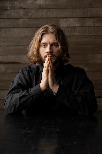 Medium shot priest praying indoors