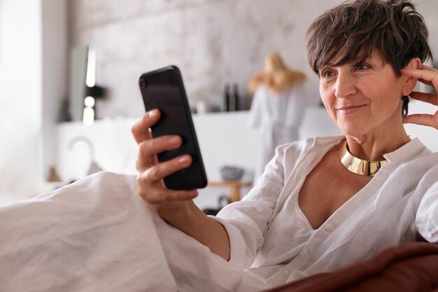 Medium shot rich woman holding smartphone