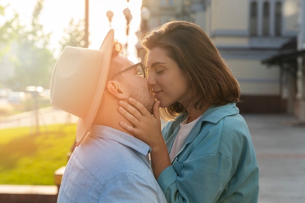 Medium shot romantic couple kissing outdoors
