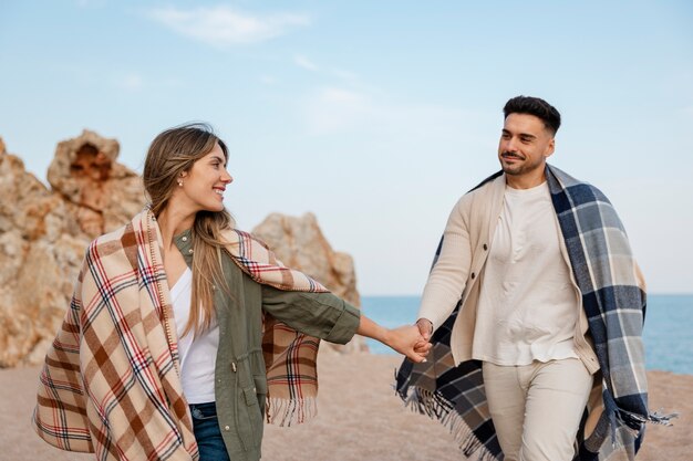 Free photo medium shot romantic couple with plaid blanket