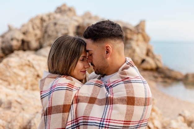 Free photo medium shot romantic couple with plaid blanket