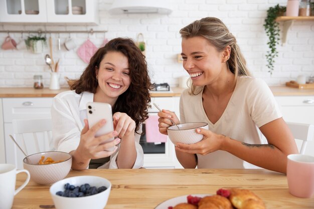 Medium shot roommates looking at smartphone