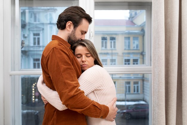 Medium shot sad couple hugging at home