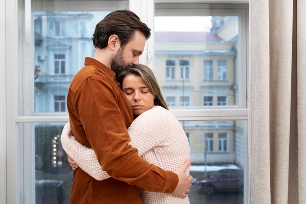 自宅で抱き締めるミディアムショット悲しいカップル