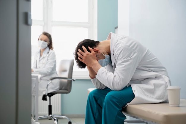 Free photo medium shot sad doctor wearing mask