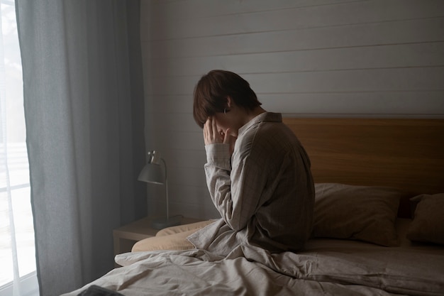 Medium shot sad woman in bedroom