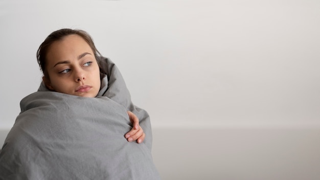 Free photo medium shot sad woman covering with blanket