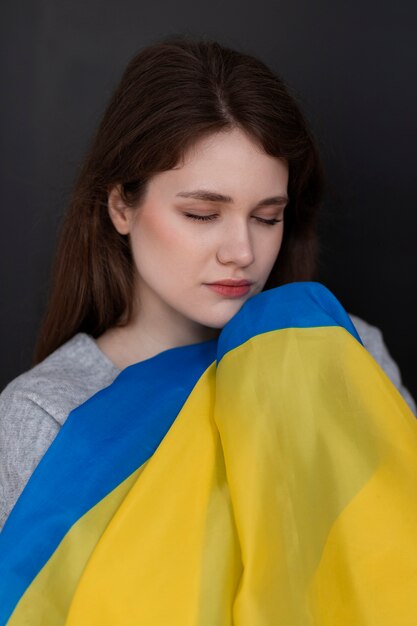 우크라이나 국기를 들고 중간 샷 슬픈 여자