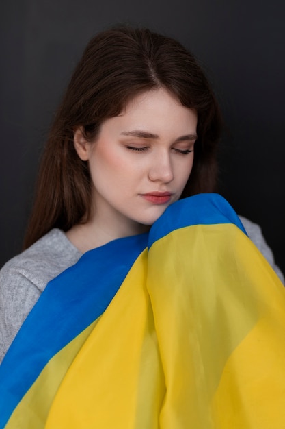 Medium shot sad woman holding ukrainian flag