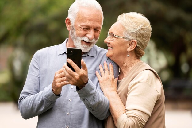 Medium shot senior couple holding phone
