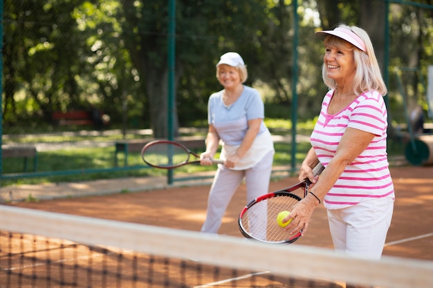 Foto gratuita amici senior di tiro medio che giocano a tennis