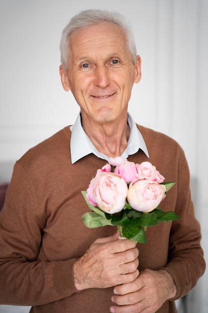 花を持っているミディアムショットの年配の男性