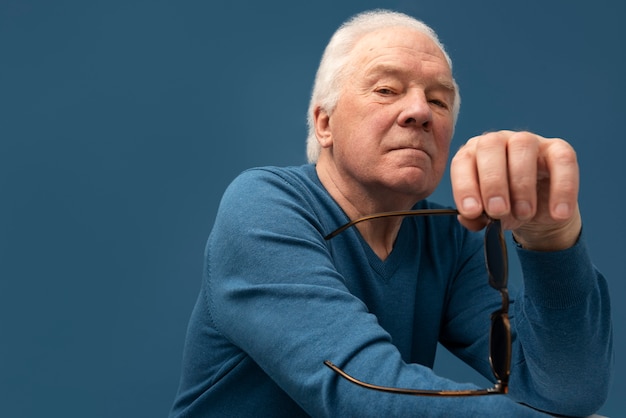 Free photo medium shot senior man holding sunglasses