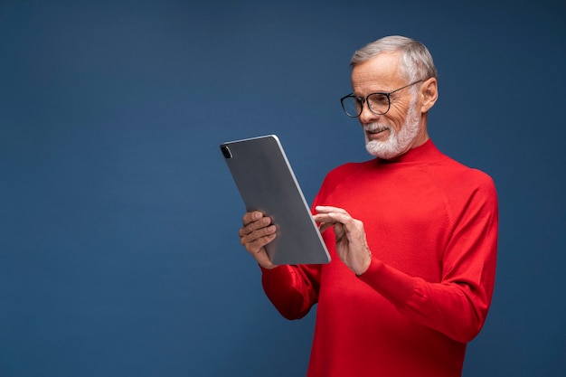 Free photo medium shot senior man holding tablet