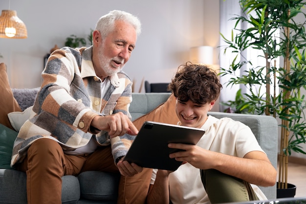 Средний снимок пожилого мужчины и ребенка с планшетом