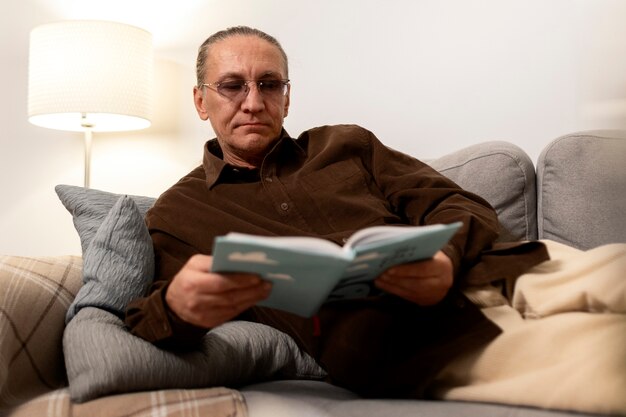 Medium shot senior man reading at home