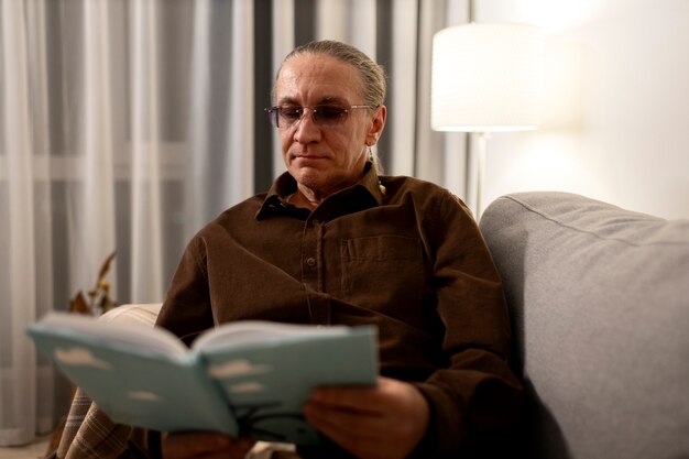 Medium shot senior man reading at home