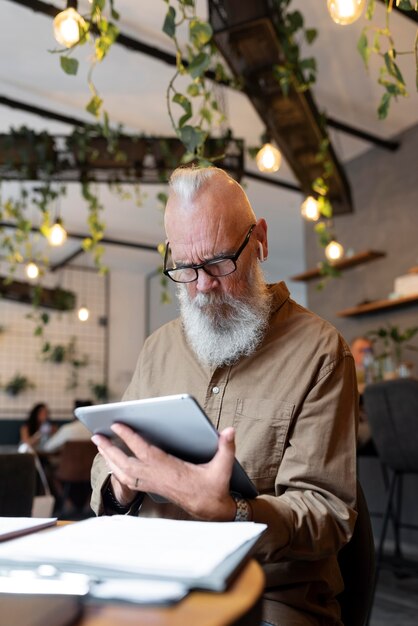 Medium shot senior man studying with device