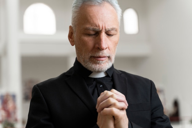 Medium shot senior priest praying at church