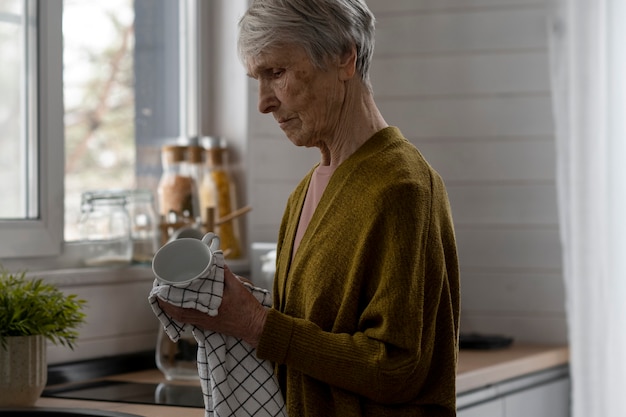 Free photo medium shot senior woman cleaning dishes