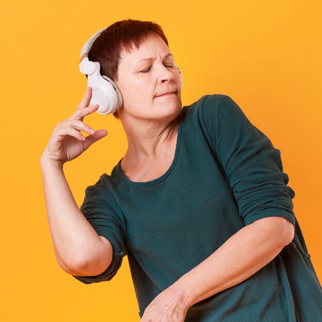 Medium shot senior woman dancing and listening music