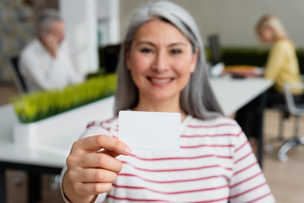 Medium shot senior woman holding business card