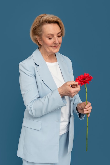 Средний план пожилой женщины с цветком