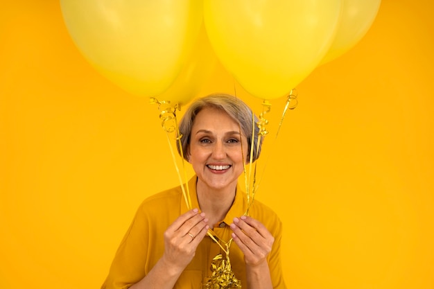 Пожилая женщина среднего роста позирует с воздушными шарами