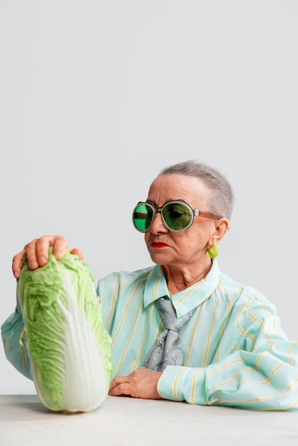 Medium shot senior woman posing with celery