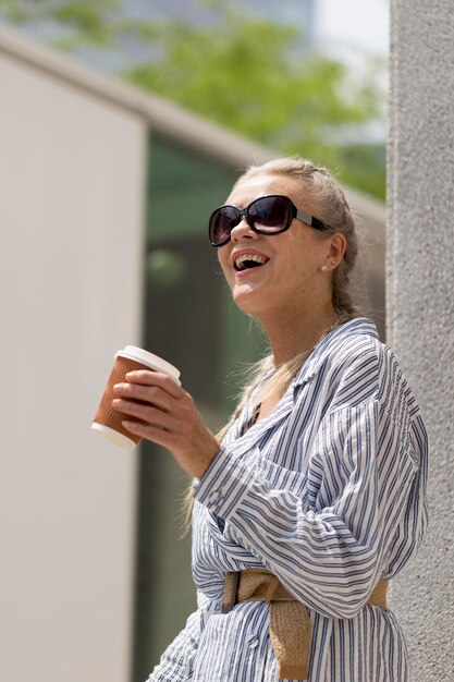 コーヒーカップとミディアムショットの年配の女性