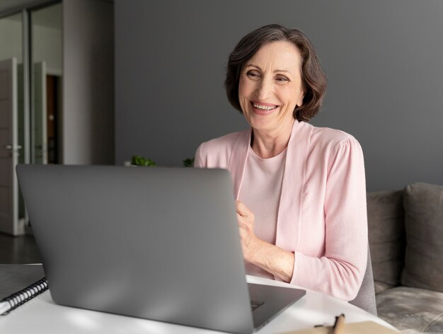 Medium shot senior woman with laptop