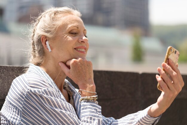 Medium shot senior woman with smartphone