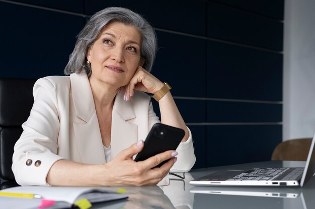 Medium shot senior woman with smartphone