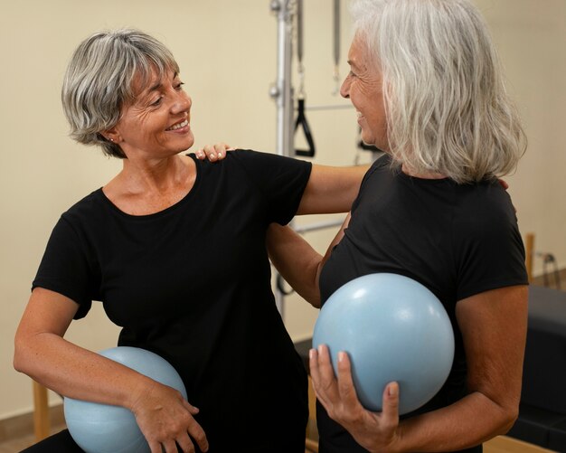 Medium shot senior women in pilates reformer class