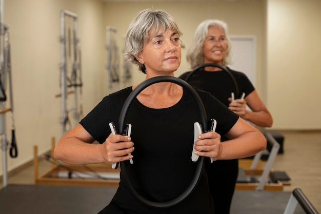 Medium shot senior women in pilates reformer class