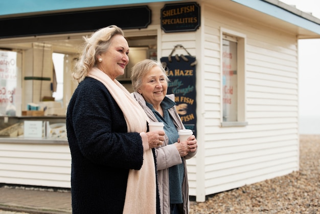 Medium shot senior women with coffee cups