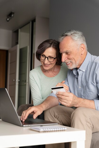 Medium shot seniors with laptop and card