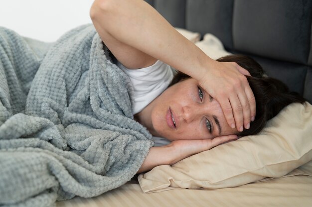 ベッドに横たわっているミディアムショットの病気の女性