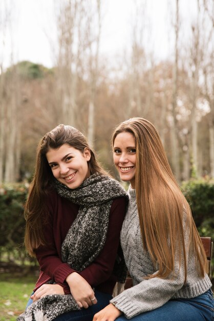 Medium shot side view of two smiling women in the park