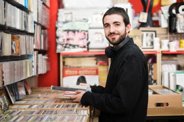 Medium shot side view of young man in music store looking at camera