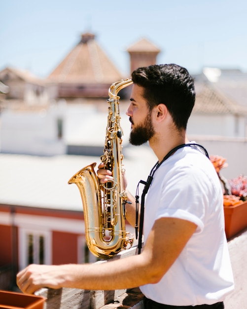 Medium shot sideways man posing with saxophone