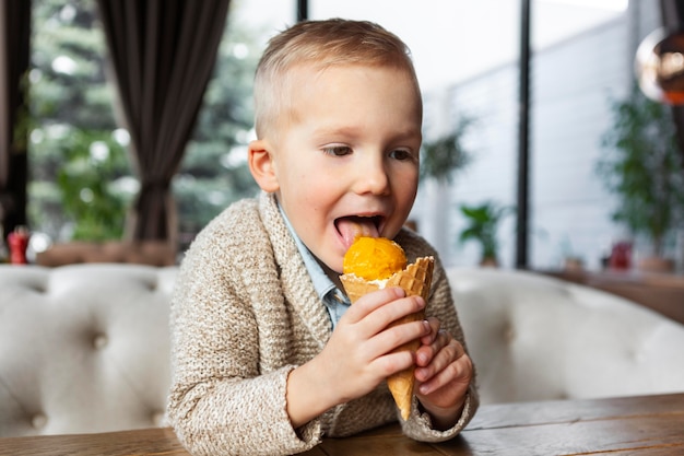 Free photo medium shot smiley boy eating ice cream