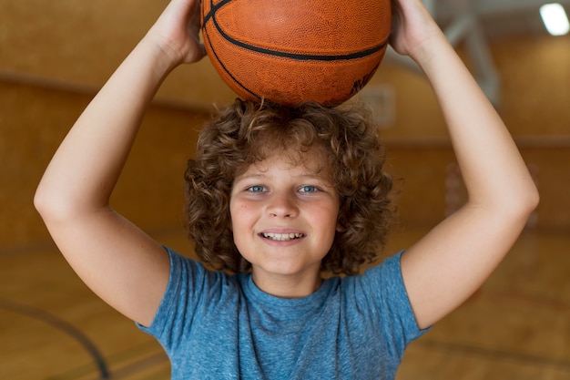 Free photo medium shot smiley boy holding basket ball