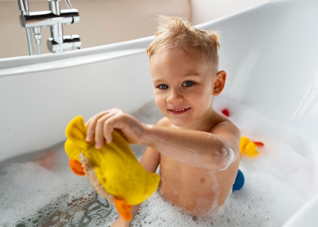 Free photo medium shot smiley boy playing in bathtub